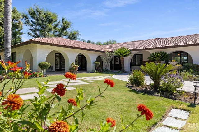 a view of a backyard with table and chairs potted plants and large tree