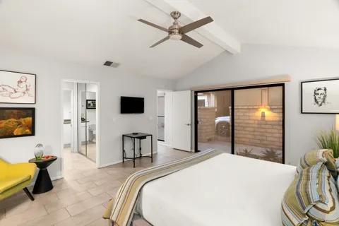 a bedroom with a bed and large mirror with a flat tv screen