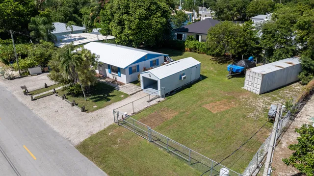 an aerial view of a house with swimming pool and large trees
