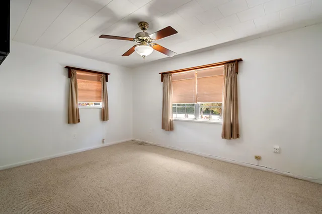 a view of an empty room with a ceiling fan window and a ceiling fan