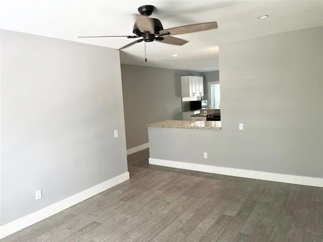 a room with a chandelier fan and wooden floor