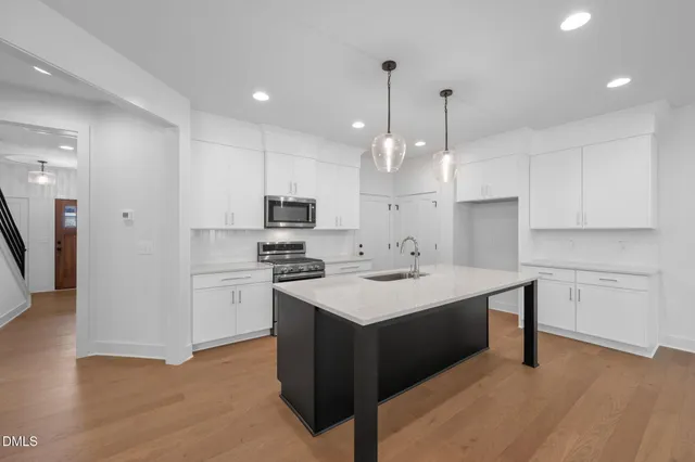 a kitchen with kitchen island a sink stainless steel appliances and white cabinets