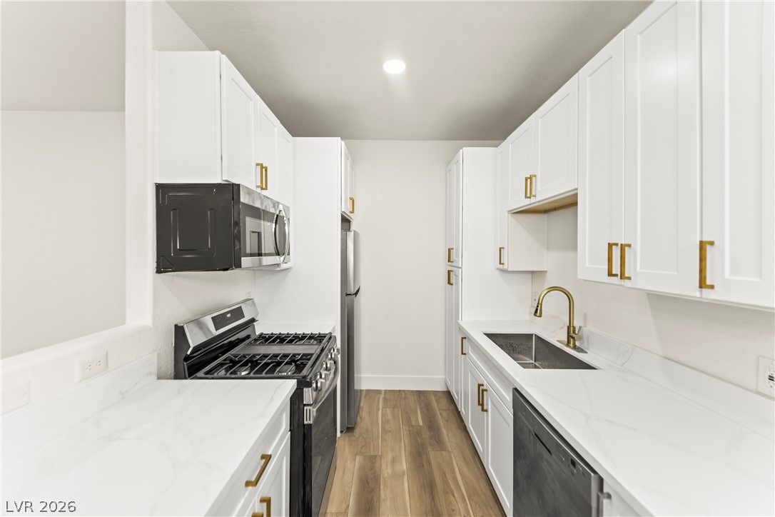 4730 East Craig Road, Unit 1053 Las Vegas, NV 89115 - Photo 2 of 32 A galley kitchen boasts white cabinetry, pristine countertops, and modern stainless steel appliances.