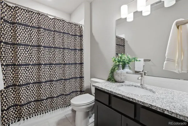 a bathroom with a granite countertop sink a toilet a mirror and shower