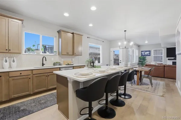 a kitchen with cabinets a sink dishwasher a stove and a dining table with wooden floor