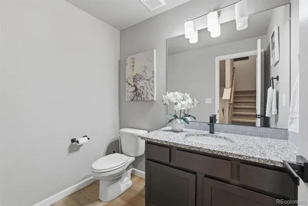 a bathroom with a granite countertop sink a toilet and mirror