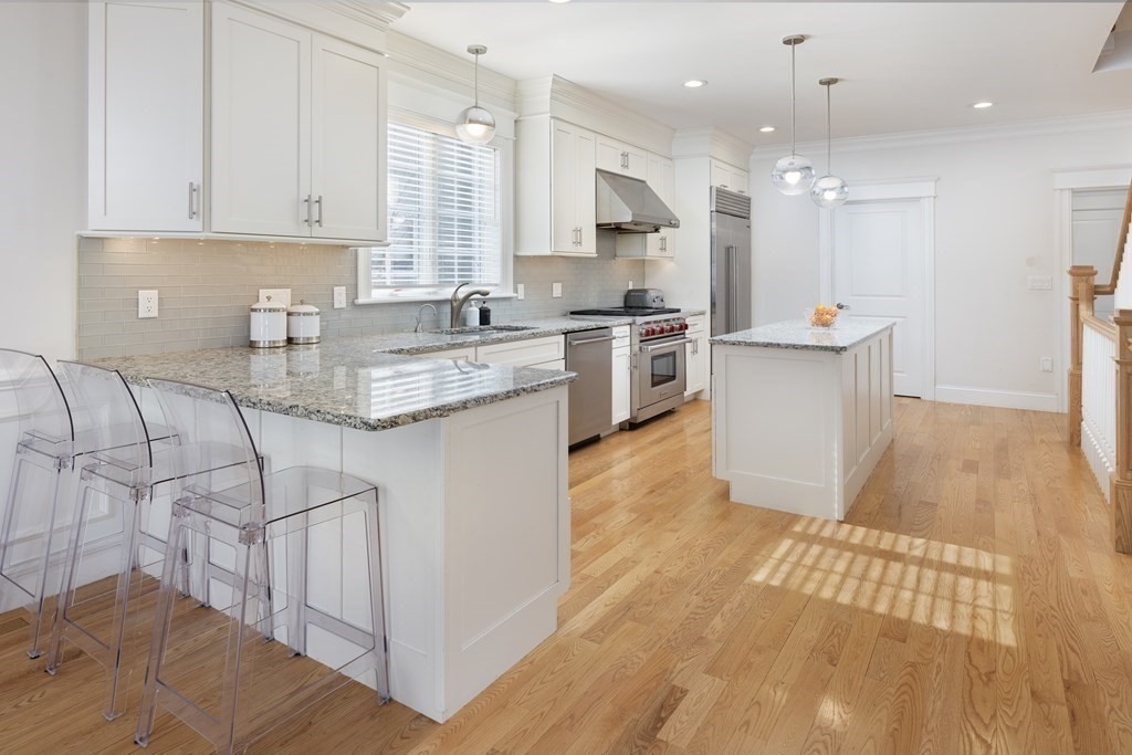 55 Kendall Road Lexington, MA 02421 - Photo 7 of 32 a kitchen with stainless steel appliances granite countertop a sink a stove a refrigerator and white cabinets with wooden floor