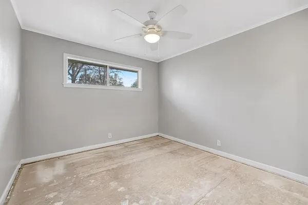 an empty room with a ceiling fan and a window