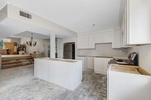 a living room with stainless steel appliances kitchen island a sink a stove a refrigerator cabinets and a counter top space