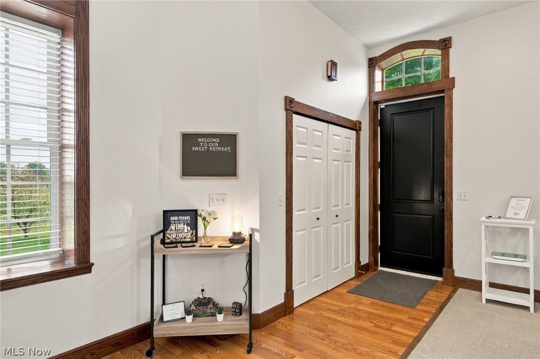 42764 Russia Road Elyria, OH 44035 - Photo 22 of 50 Hardwood flooring, white paneled bifold closet doors, dark wood trim, black entry door with transom window, and a window with horizontal blinds