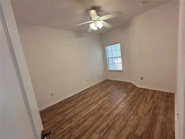 an empty room with a window and ceiling fan