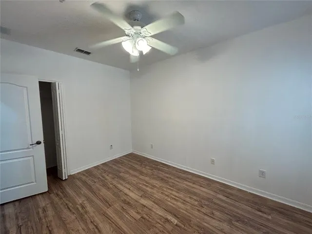 an empty room with wooden floor and ceiling fan