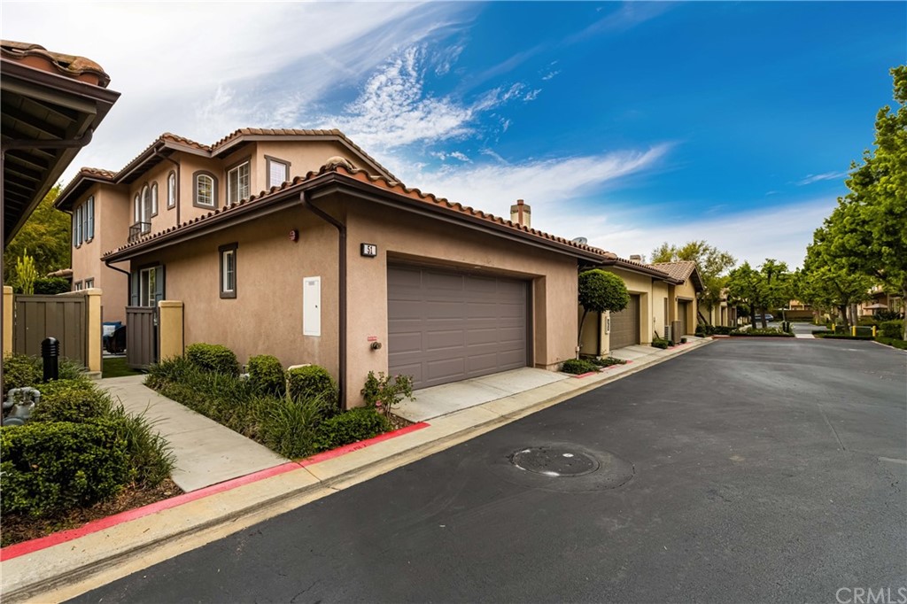 51 Secret Garden Irvine, CA 92620 - Photo 18 of 28 a front view of a house with a yard and garage
