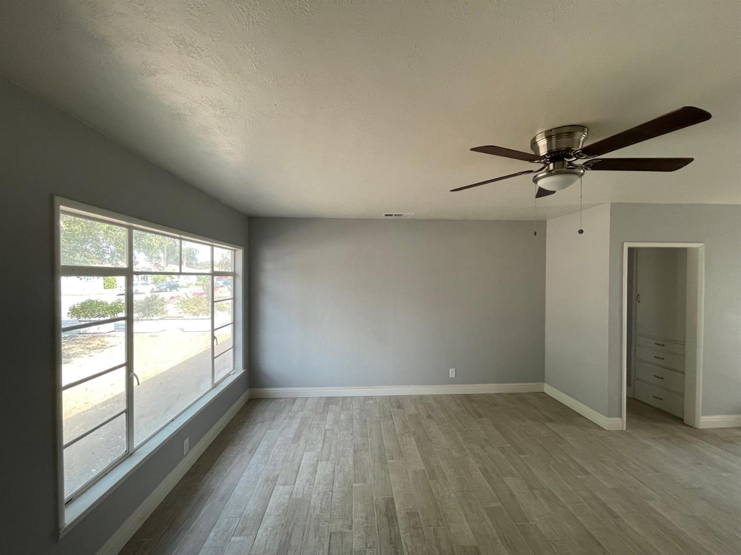 1246 South Klein Avenue Reedley, CA 93654 - Photo 3 of 10 an empty room with wooden floor fan and windows