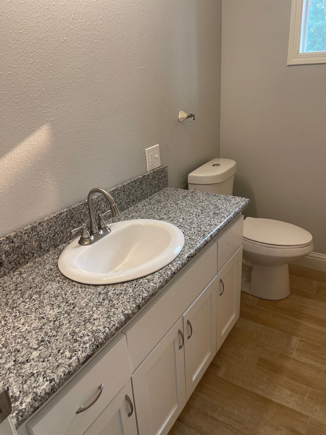 1246 South Klein Avenue Reedley, CA 93654 - Photo 9 of 10 a bathroom with a granite countertop sink a toilet and a mirror