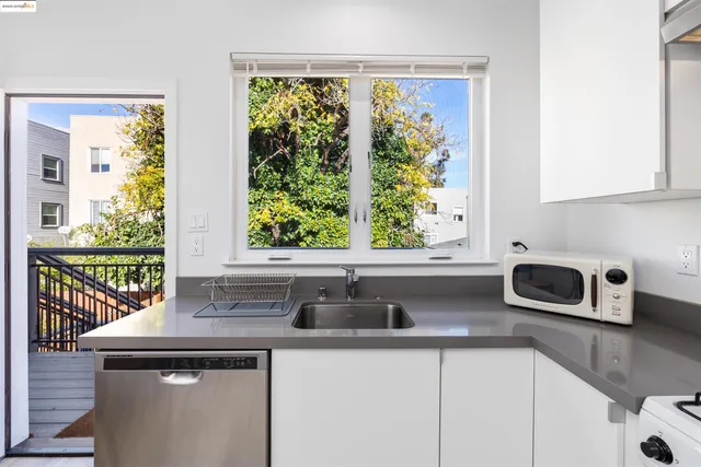 a white kitchen with stainless steel appliances a stove a sink a refrigerator and cabinets