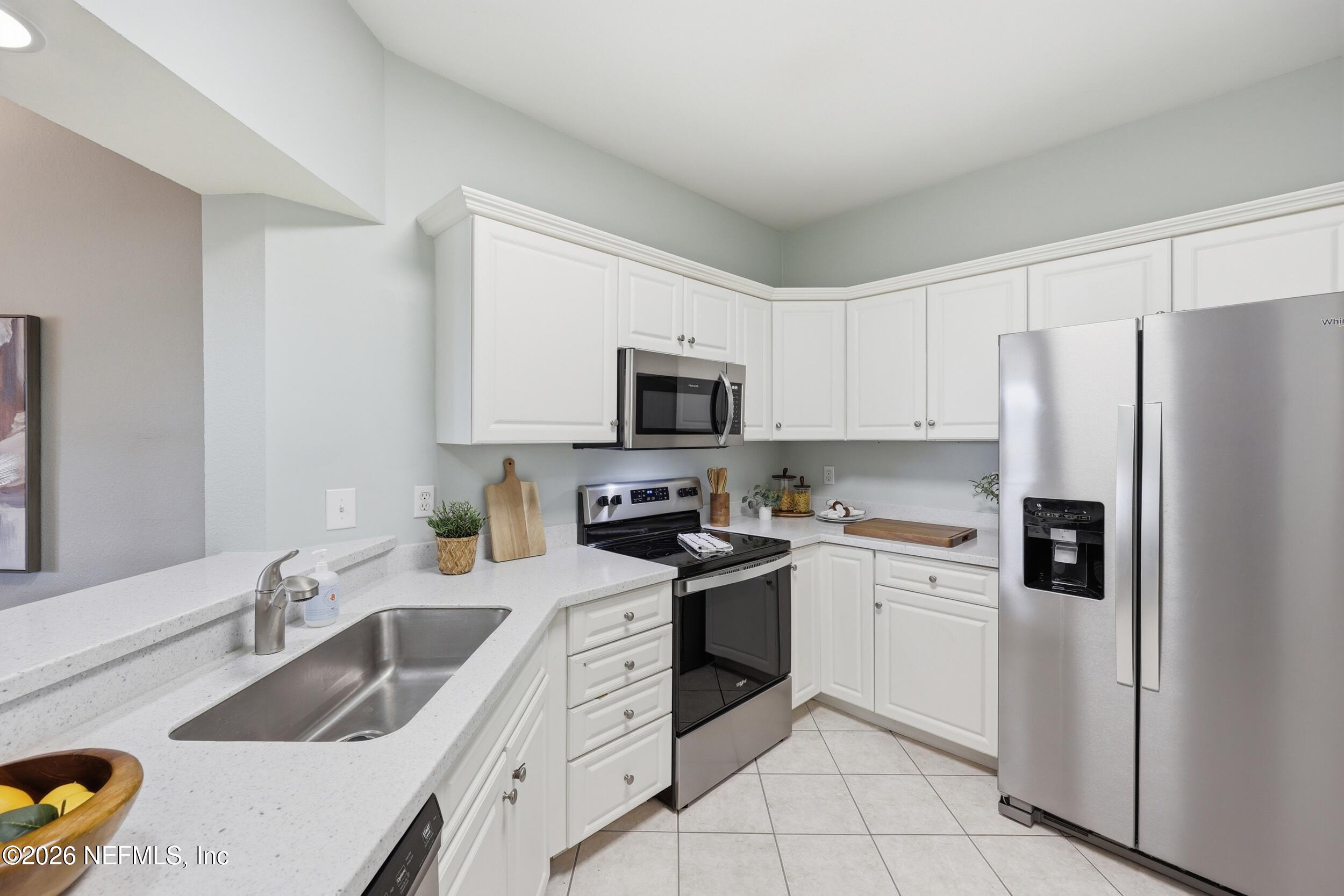 1529 Vista Cove Road St. Augustine, FL 32084 - Photo 5 of 75 a kitchen with granite countertop a sink a stove a refrigerator and white cabinets