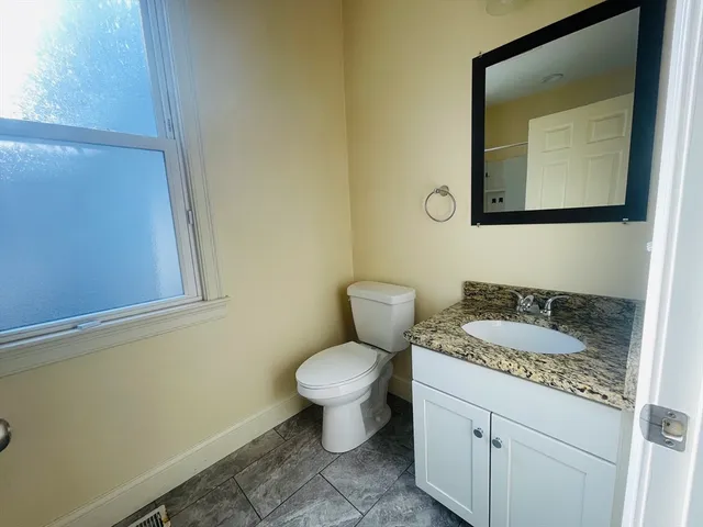a bathroom with a granite countertop toilet sink and mirror