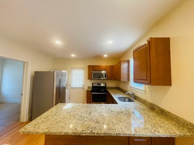 a kitchen with granite countertop a refrigerator and a sink
