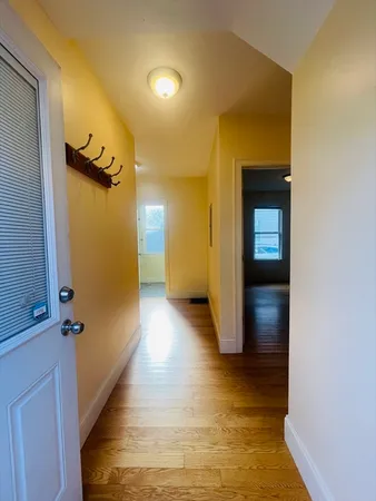 a view of a hallway with wooden floor and a bathroom