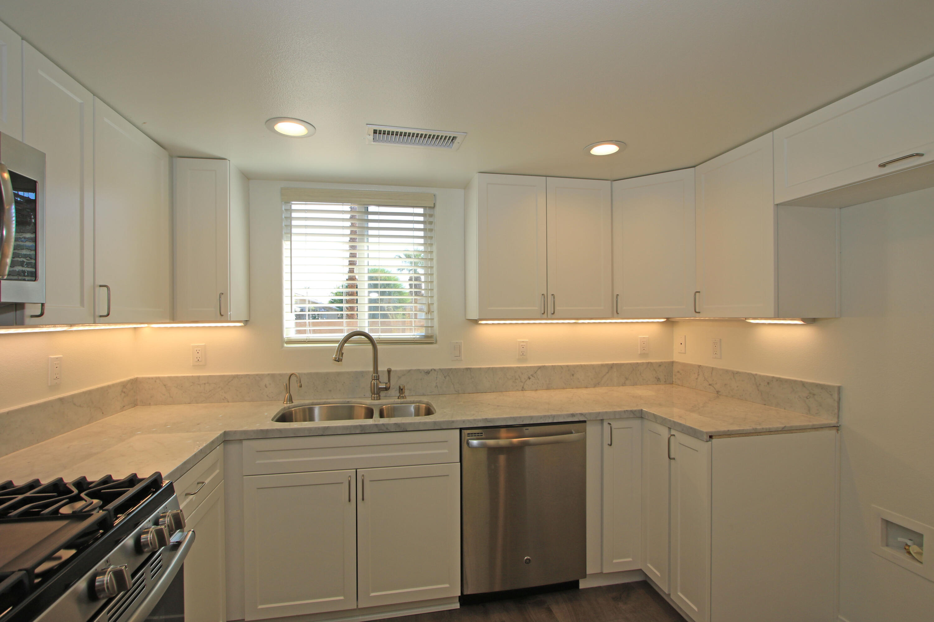 51845 Eisenhower Drive La Quinta, CA 92253 - Photo 13 of 35 a kitchen with a sink cabinets appliances and a window