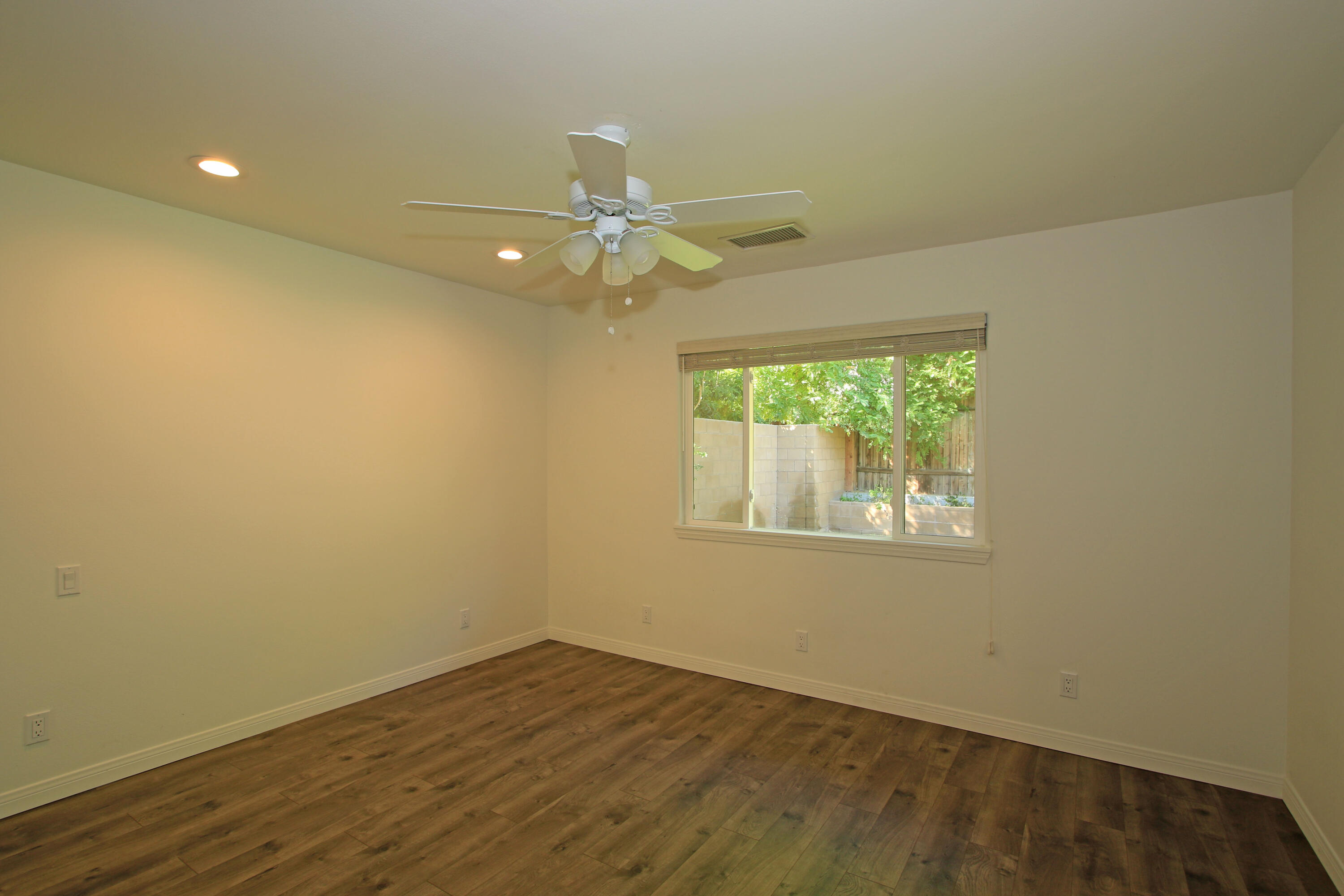 51845 Eisenhower Drive La Quinta, CA 92253 - Photo 18 of 35 an empty room with wooden floor fan and windows