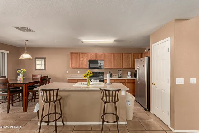 a kitchen with stainless steel appliances a dining table chairs a refrigerator and cabinets