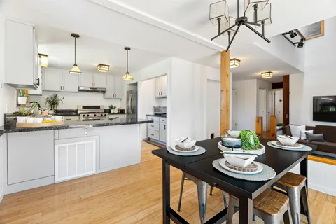 a kitchen with stainless steel appliances kitchen island granite countertop a dining table chairs and white cabinets