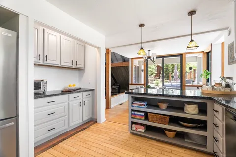 a kitchen with stainless steel appliances kitchen island granite countertop a stove a refrigerator and a wooden floors