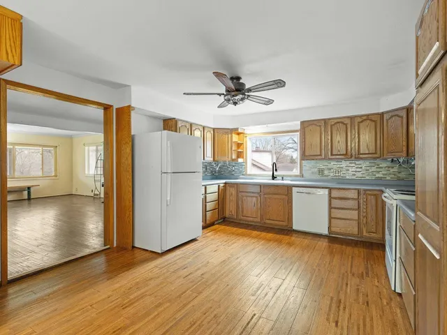 a large kitchen with stainless steel appliances granite countertop a refrigerator a sink dishwasher a stove with wooden floors and cabinets