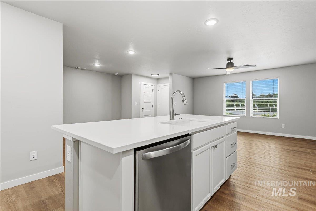 12475 West Victory Road Boise, ID 83709 - Photo 13 of 26 Kitchen island featuring a white countertop, undermount sink, and stainless steel dishwasher