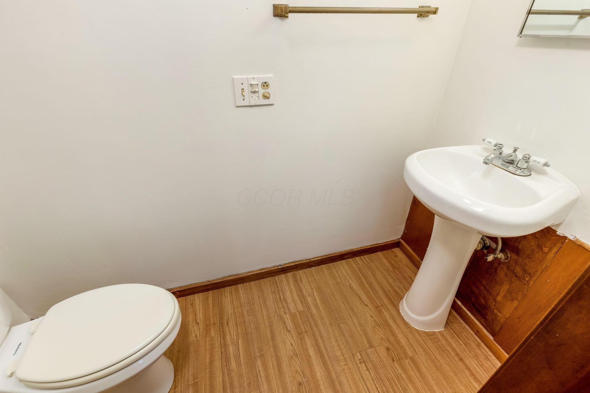 14823 Cleveland Road Southwest Pataskala, OH 43062 - Photo 29 of 57 Pedestal sink with chrome faucet, toilet, and wood-finish flooring