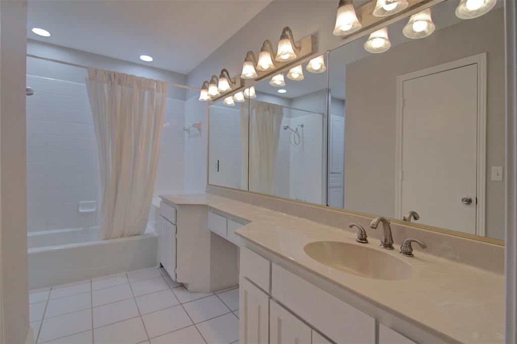 14822 Sopras Circle Addison, TX 75001 - Photo 17 of 33 a bathroom with a sink a large mirror and a shower