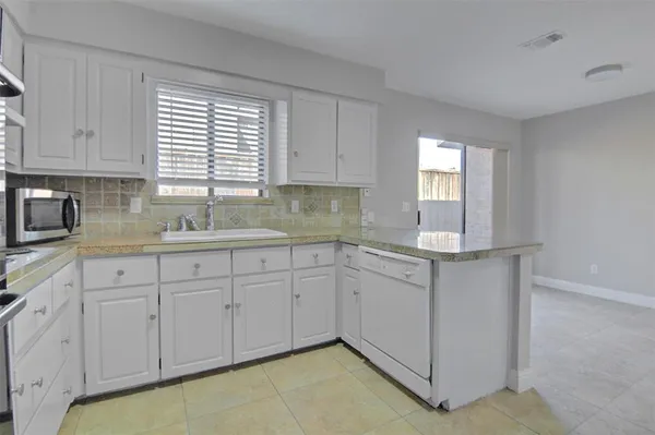 a kitchen with white cabinets a sink and dishwasher next to a window