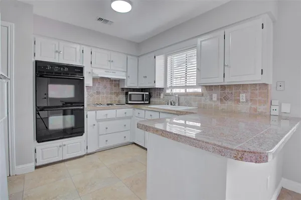 a kitchen with granite countertop white cabinets white stainless steel appliances and a sink