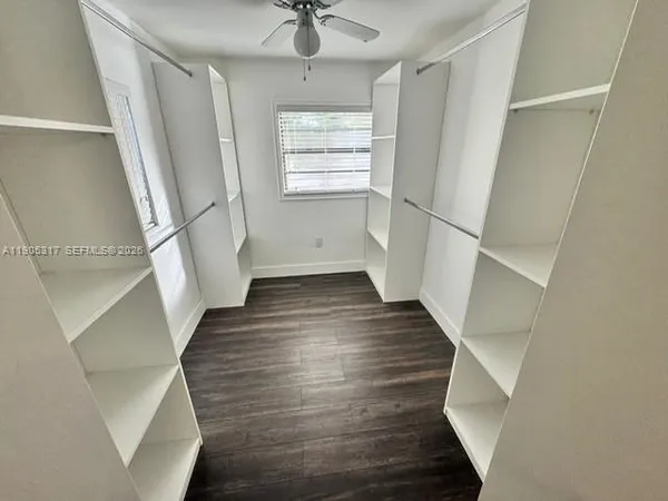 an empty room with wooden floor fan and windows