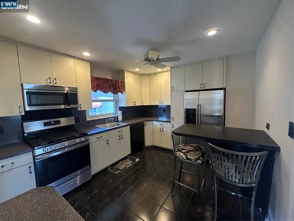 a kitchen with stainless steel appliances a stove a sink a microwave a refrigerator and cabinets