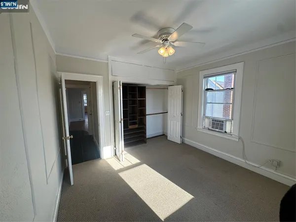 an empty room with chandelier fan and windows