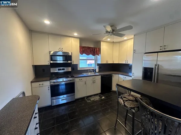 a kitchen with stainless steel appliances a stove a sink a microwave a refrigerator and cabinets