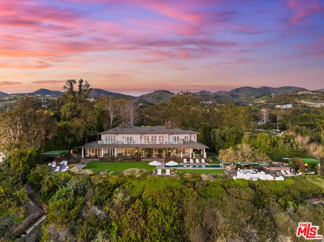 a view of a brick house with a yard and large trees