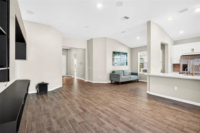 a view of a living room a kitchen with furniture and wooden floor