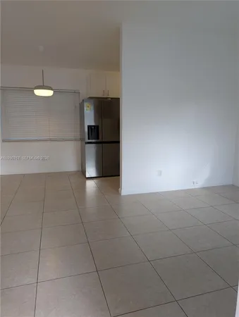 a view of a refrigerator in kitchen and empty room