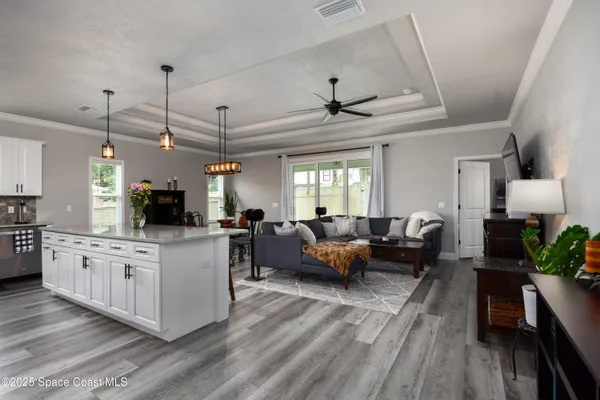 a living room with furniture and a flat screen tv with kitchen view