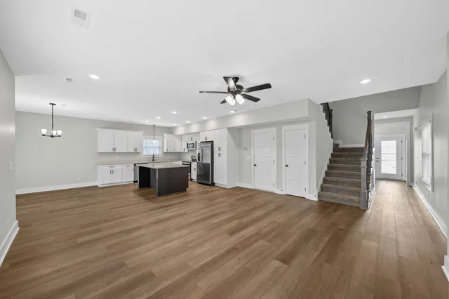 a view of an empty room with wooden floor and a ceiling fan