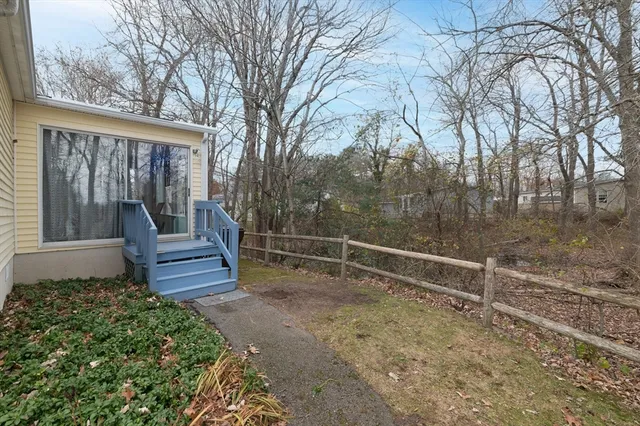 a view of wooden house with a bench next to a yard