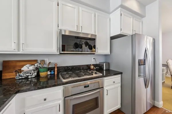 a kitchen with stainless steel appliances granite countertop white cabinets a refrigerator and a stove