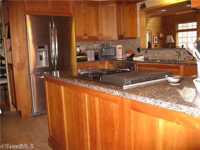 6715 Ventwood Road Climax, NC 27233 - Photo 4 of 16 Kitchen. The kitchen has a built-in granite table at the breakfast area, as well as, two pantries, cherry cabinets w/granite c-tops, gas cook top, dishwasher, double SS sink, tile backsplash, pendant lights, tile floor. Gorgeous exposed beams at the ceiling.