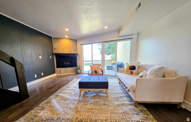 5265 South Rome Beauty Park Murray, UT 84123 - Photo 13 of 35 Living room featuring dark wood finished floors, a tile fireplace, wooden walls, recessed lighting, and a textured ceiling