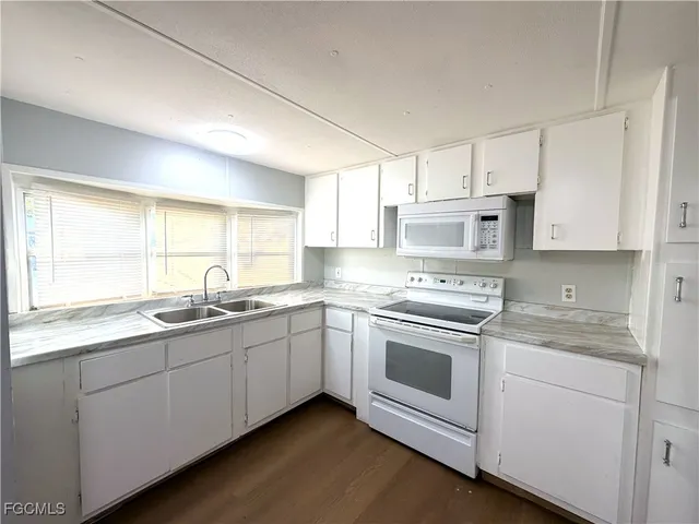 a kitchen with stainless steel appliances granite countertop white cabinets a sink a stove a window and white