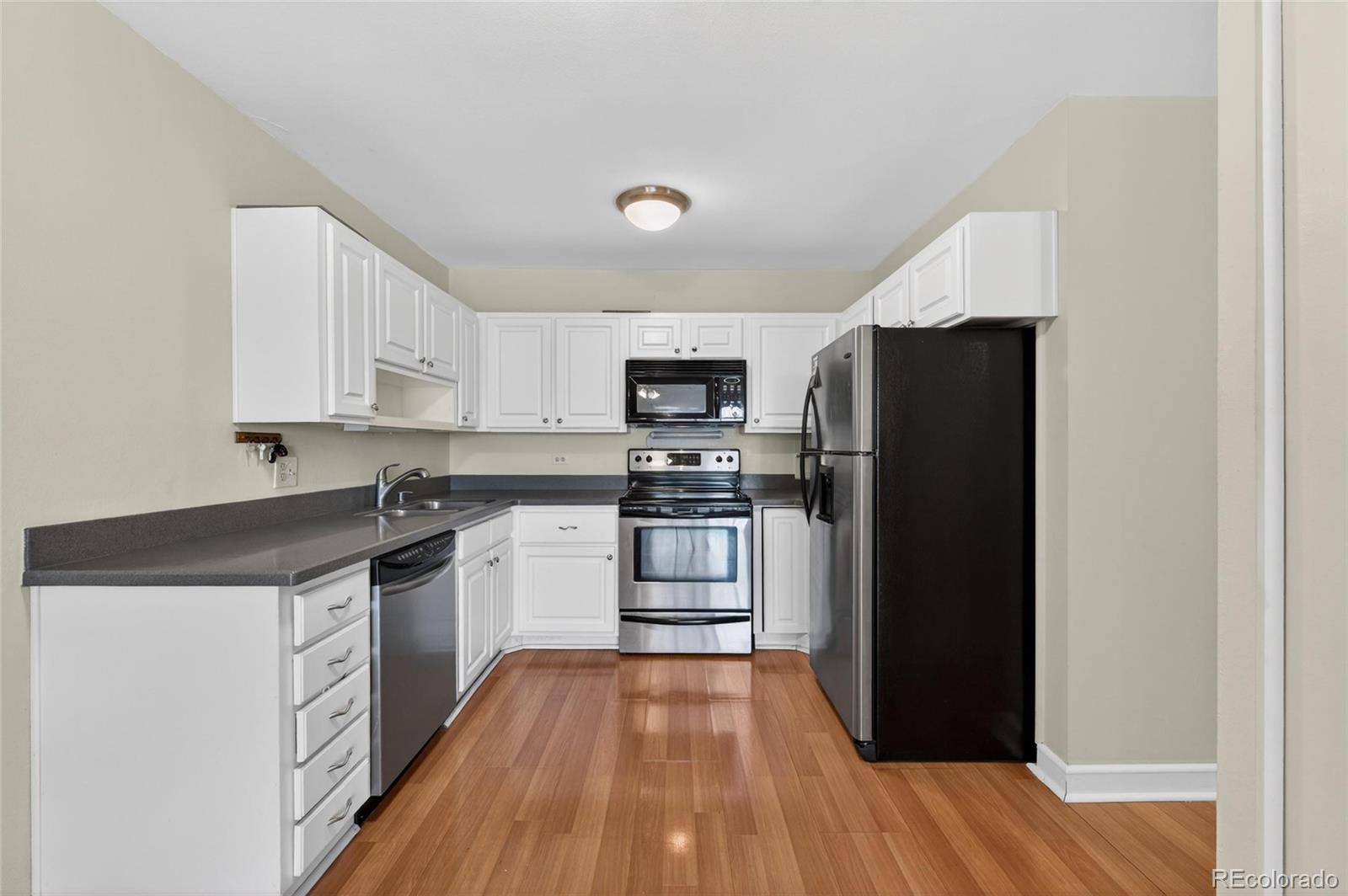 720 South Clinton Street, Unit B1 Denver, CO 80247 - Photo 4 of 19 a kitchen with granite countertop a refrigerator and a stove top oven